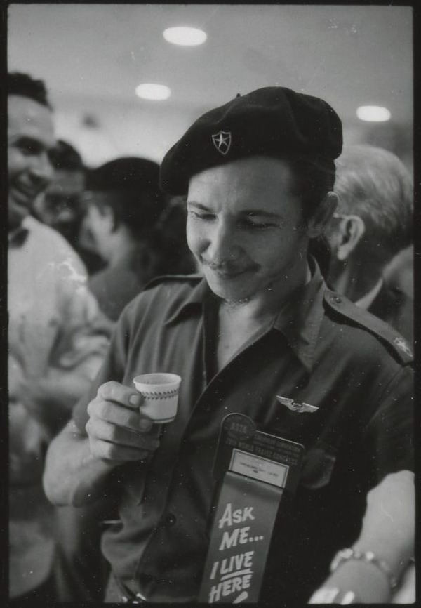 Raúl Castro saludando a los delegados en el Havana Hilton, sede de la Convención de la ASTA, con una tacita de café espresso cubano y portando una credencial con la inscripción (en inglés): «Pregúntame… yo vivo aquí».